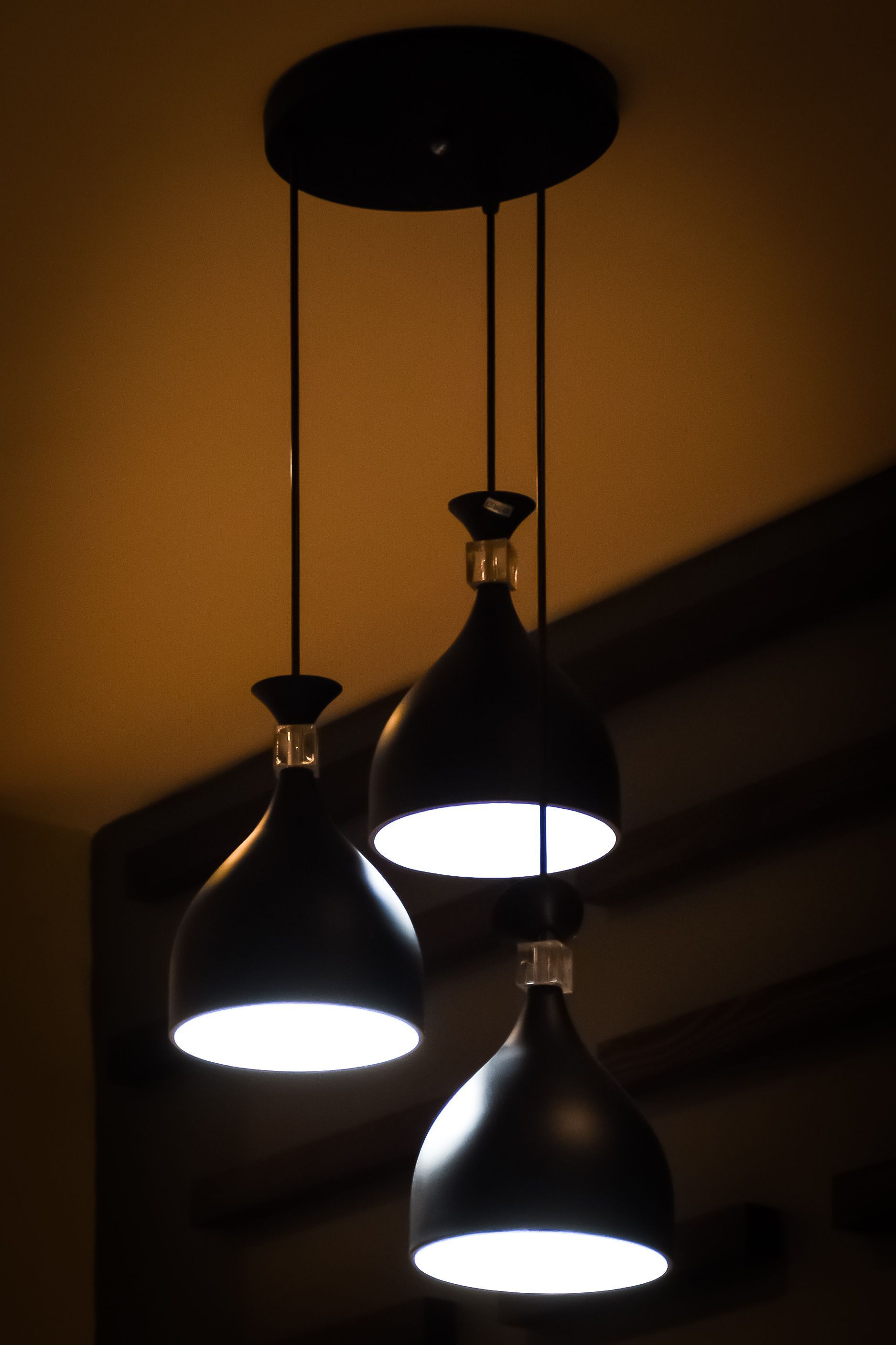 Modern black pendant lights hanging indoors, casting a warm glow.